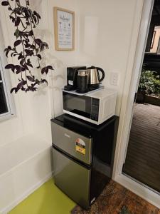a microwave sitting on top of a counter with a coffee pot at Zen Cabin in Mount Maunganui