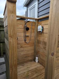 a shower in a wooden building with a wooden wall at Zen Cabin in Mount Maunganui +13 photos
