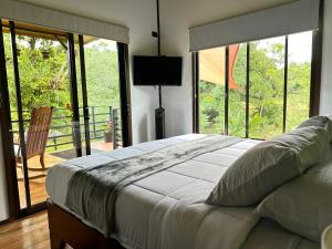 a bedroom with a bed and a balcony with a television at Ceibo Lodge in Bijagual