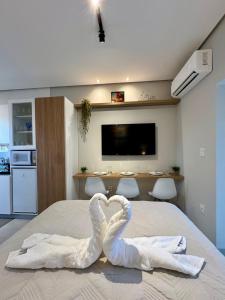 1 dormitorio con 2 toallas en forma de cisne en una cama en Studio aconchegante com garagem privativa e varanda, en Montes Claros