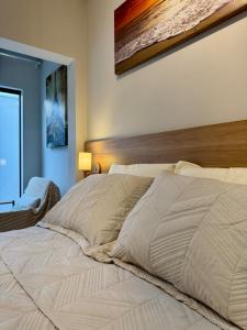 Un dormitorio con una gran cama blanca con cabecero de madera. en Studio aconchegante com garagem privativa e varanda, en Montes Claros