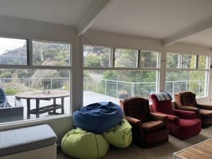 a living room with chairs and a table and windows at Beachfront Tranquility in Tikao Bay in Wainui