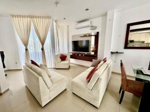 a living room with two white chairs and a television at Apartamento de lujo en Piura in Piura