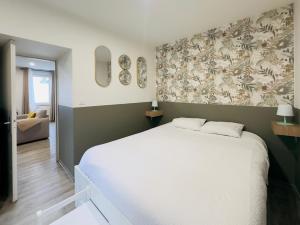 1 dormitorio con cama blanca y pared con papel pintado en Idéal couples & pro - Patio extérieur- Proche centre ville et gare - Promenade au bord de la Charente - Parking à proximité - Wifi très haut debit - Équipement premium -Netflix, en Angulema
