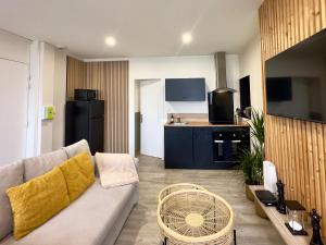 Una sala de estar con un sofá y una cocina. en Idéal couples & pro - Patio extérieur- Proche centre ville et gare - Promenade au bord de la Charente - Parking à proximité - Wifi très haut debit - Équipement premium -Netflix, en Angulema