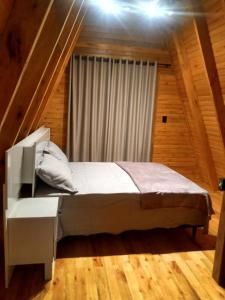 a bedroom with a bed in a wooden room at Cabana Encanto da Mata in Santa Maria do Erval