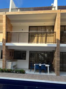 ein Haus mit einem Balkon mit einem Tisch und Stühlen in der Unterkunft Casa em condomínio na praia in Cabedelo