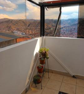 a balcony with potted plants and a view of a city at Sumaq Tika in Cusco