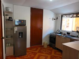 a small kitchen with a refrigerator and a window at Sumaq Tika in Cusco