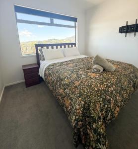 una camera da letto con un letto con una grande finestra di Cosy Luxe --Modern 3 bedroom home in Johnsonville a Wellington