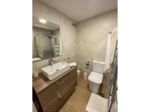 Un baño con lavabo, inodoro y espejo. en Apartment with Sea Views in Mijas Costa, en Mijas Costa 7 fotos más