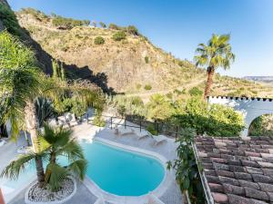 a swimming pool with palm trees and a mountain at Yoga and Relaxation Retreat in the Heart of Nature in Carratraca
