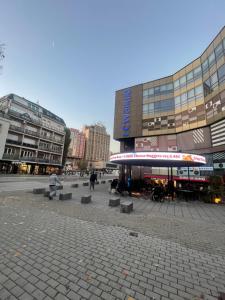 a group of people sitting on benches in front of a building at Prishtina Center Apartment in Pristina
