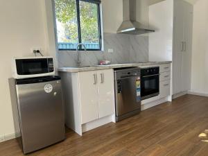 a kitchen with stainless steel appliances and a microwave at Cosy and convenient accommodation in Springvale