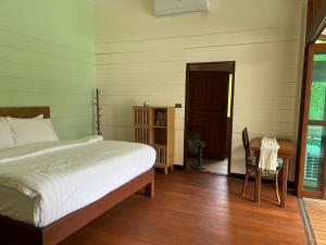 a bedroom with a bed and a desk and a door at À La Koh Kood Resort in Ko Kood