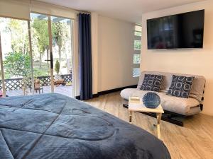 een slaapkamer met een bed, een bank en een televisie bij Suite de lujo con naturaleza y BBQ cerca de Cuenca in Cuenca