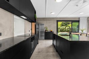 eine Küche mit schwarzen Schränken und einer großen Insel in der Unterkunft Private Beach Access - Mangawhai in Mangawhai