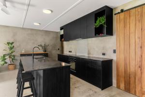 eine Küche mit schwarzen Schränken und einer Pflanze an der Wand in der Unterkunft Private Beach Access - Mangawhai in Mangawhai