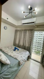 a bedroom with a bed and a large window at Shell Residence MOA Pasay by Kathy in Manila +20 photos