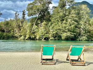 twee stoelen op een strand naast een rivier bij Alma Andina in Puelo