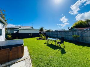 een achtertuin met een tafel en stoelen en een hek bij The Bach - Spa Pool, Pets, Scooters & Family Friendly in Whitianga