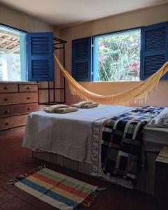 a bedroom with a hammock bed and two windows at Casa Charme Jericó Guaramiranga in Guaramiranga