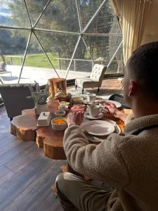 Een man aan een tafel met eten erop. bij Alma Andina in Puelo