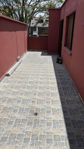 a patio with a red wall and a brick sidewalk at Real Audiencia Living in Quito +4 photos