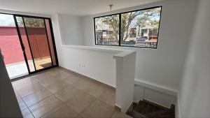 an empty living room with two windows and a staircase at Real Audiencia Living in Quito
