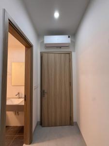 ein Badezimmer mit Holztür und einer Klimaanlage an der Decke in der Unterkunft Creamy home - Homestay Vinhomes Ocean Park 3 in Ðình Loan