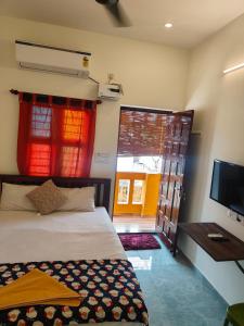 a bedroom with a bed and a television and a door at Buddha Home stay in Mahabalipuram