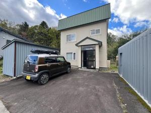een zwart busje geparkeerd voor een huis bij Kamui Adventure House in Asahikawa