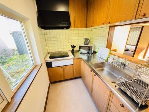 a small kitchen with a sink and a microwave at Kamui Adventure House in Asahikawa