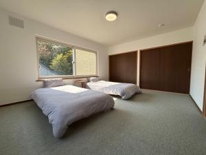 twee bedden in een kamer met een raam bij Kamui Adventure House in Asahikawa