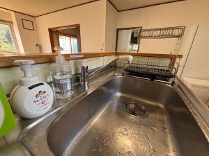 een keukengootsteen met een fles zeep en een spiegel bij Kamui Adventure House in Asahikawa +48 foto's