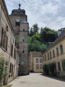 ein Gebäude mit einem Uhrenturm darauf in der Unterkunft Le Saint-Georges - Gîte de charme à Faucogney au pied des 1000 Étangs in Faucogney-et-la-Mer