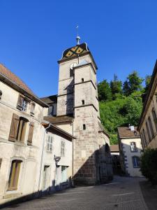 ein altes Gebäude mit einem Uhrturm auf einer Straße in der Unterkunft Le Saint-Georges - Gîte de charme à Faucogney au pied des 1000 Étangs in Faucogney-et-la-Mer