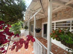 a porch of a house with red flowers on it at Casa vacacional El Oasis in Villavicencio