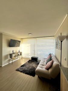 Depto a pasos de la playa 5-6 personas - La Serena في لا سيرينا: غرفة معيشة مع أريكة أمام نافذة