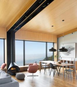 ein Wohnzimmer mit Kamin, Tisch und Stühlen in der Unterkunft Sky House Boutique Seaside Retreat With Cinema Near Dillon Beach in Dillon Beach