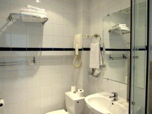a white bathroom with a toilet and a sink at Hôtel du Square d'Anvers in Paris