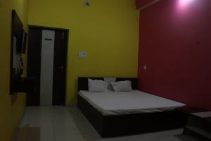 a bed in a room with a red and yellow wall at OYO 86877 Hotel Bhuneshwar Inn in Rāmgarh