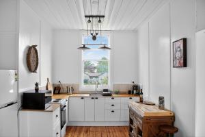 eine Küche mit weißen Schränken und einem Fenster in der Unterkunft Cedar Cottage Daylesford in Daylesford