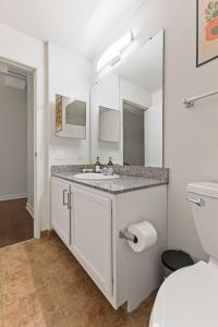 a white bathroom with a sink and a mirror at New Skywalk Access- Downtown Work Retreat- Sleeps8 in Indianapolis