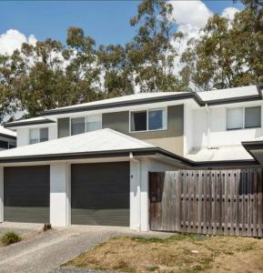a house with two garage doors and a fence at Syldah Stay Mango Hills in North Lakes