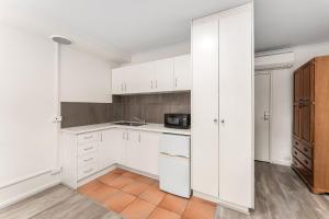 Una cocina con gabinetes blancos y un microondas. en Box Hill Studio Apartment 2, en Box Hill