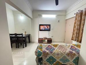 een slaapkamer met een bed en een televisie aan de muur bij Ideal 2BHK for Families & Work Trips in Bangalore