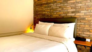 スウォンにあるHotel Biz Suwonのレンガの壁のある部屋にあるベッド