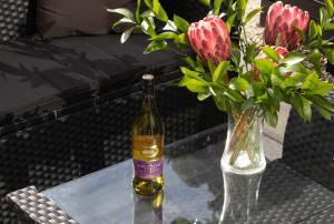 a bottle of wine and a vase of flowers on a table at City Living Unit 3 - 5 min stroll to CBD in New Plymouth +8 photos