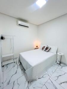 a white bedroom with a bed with a lamp on it at Casa de condomínio em Paripueira com piscina e perto da praia in Paripueira